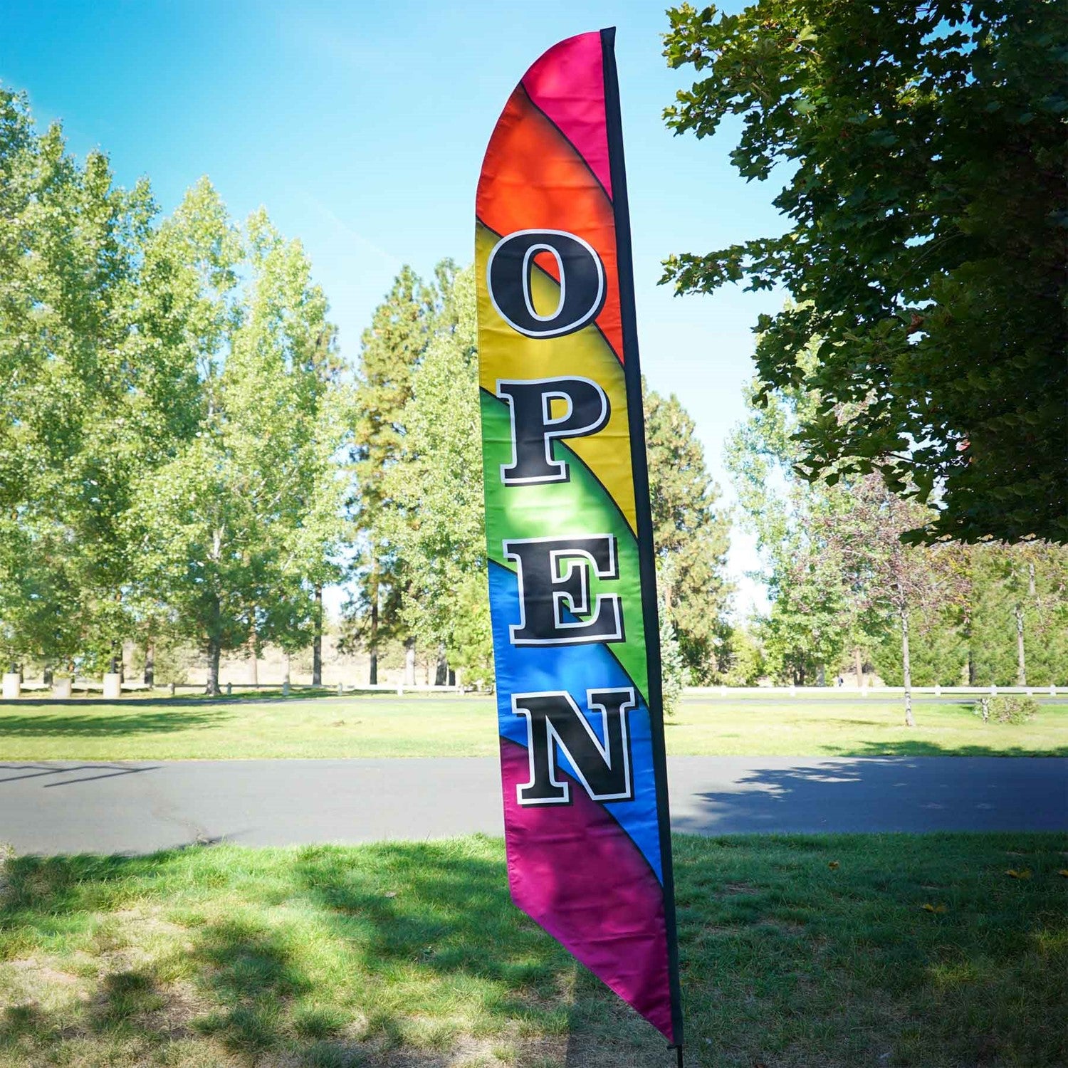 8' Heavy Duty Open Double-Sided Feather Banner displaying a colorful rainbow design outdoors, attracting attention to a storefront.