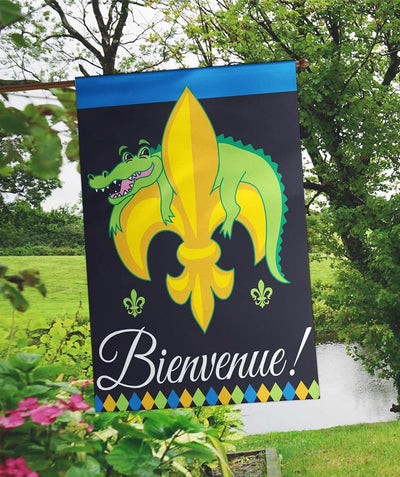 29x42 Bienvenue alligator banner flag double applique showing green alligator with stylized features and French 'Bienvenue' script on a neutral background, hanging on a porch pole.