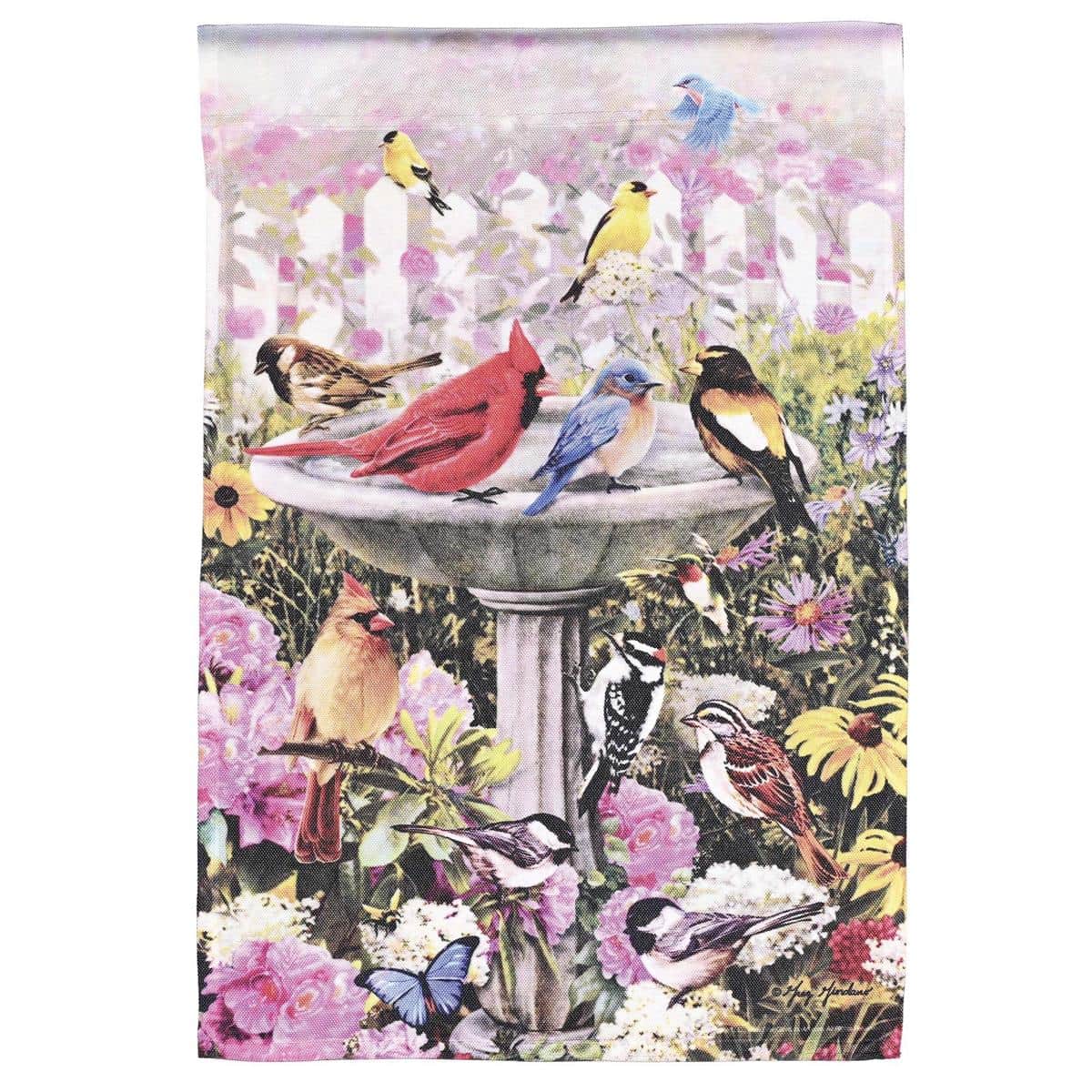 13x18 Birdbath Garden Flag with printed birds and floral accents, durable polyester fabric, shown mounted on a small garden flag pole near planters for porch and lawn display.