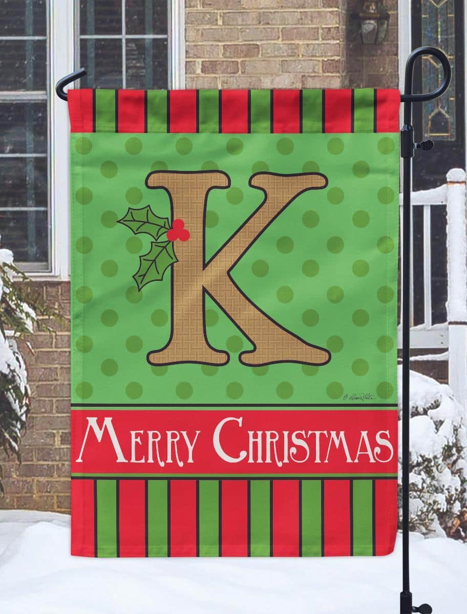 13x18 burlap Christmas monogram K garden flag with double applique holly accents displayed on a yard flag stand for porch or garden seasonal decor