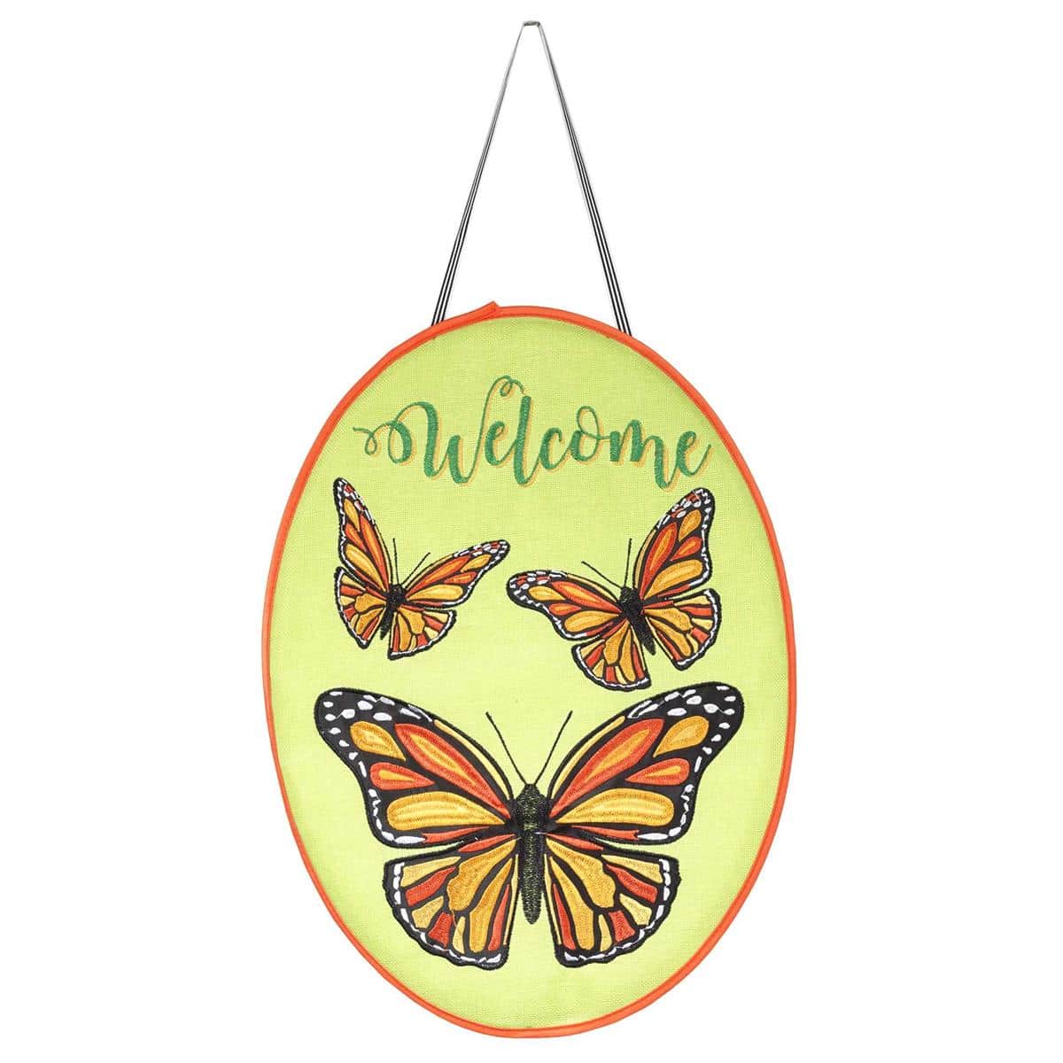 Rustic burlap door banner with embroidered butterflies and stitched "Welcome" text hanging on a farmhouse entry door, showing texture and layered applique details.