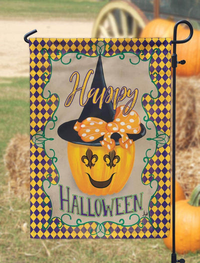 Close-up of 13x18 Halloween garden flag with ornate fleur-de-lis symbol, bold black and orange print, weather-resistant polyester, and top pole sleeve outdoors