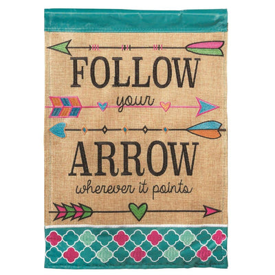 Rustic Follow Your Arrow burlap banner flag 29x42 with double applique arrows and bold lettering, shown hanging on a porch pole beside potted plants and a wooden bench.