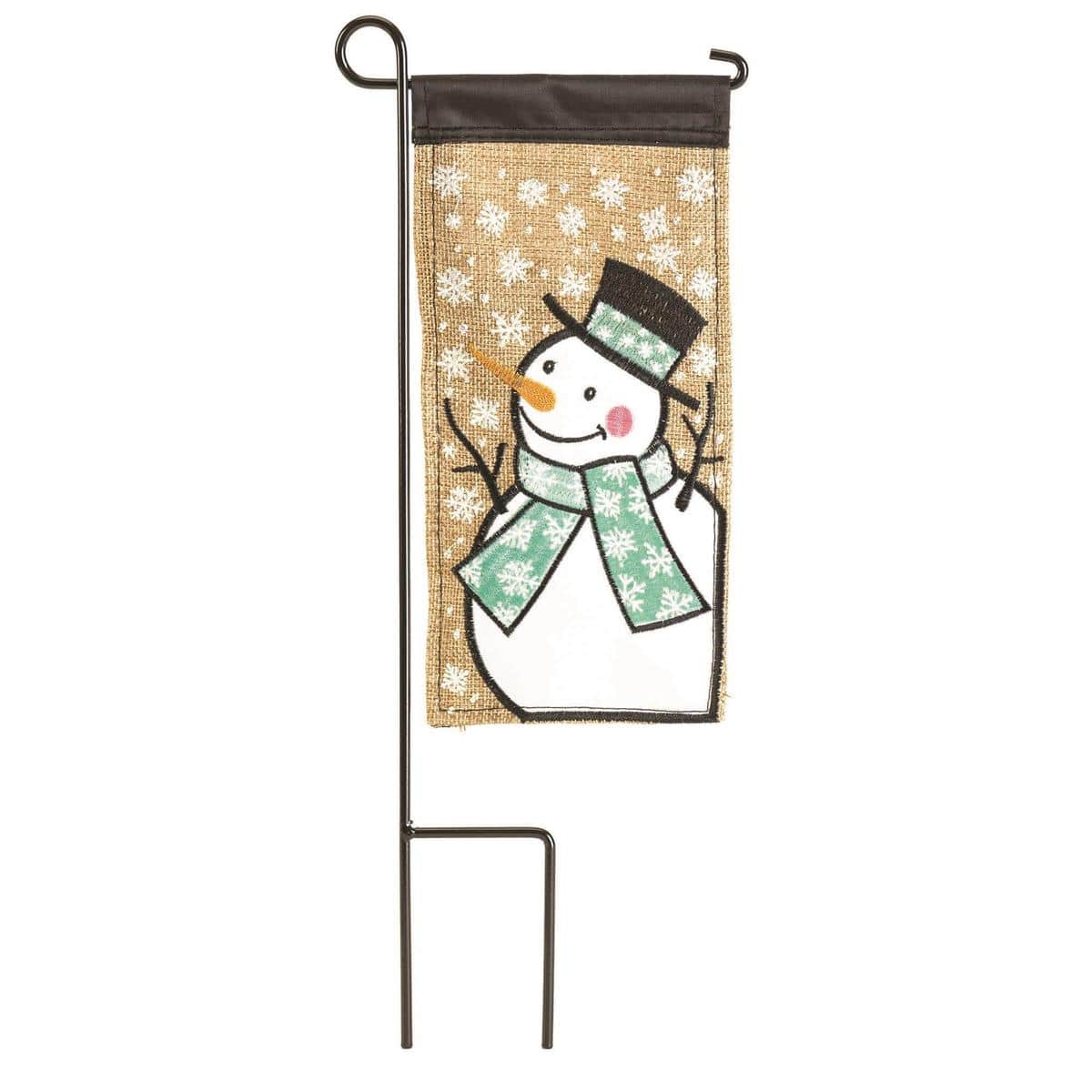 Close-up photo of Mini Snowman 4x8 mini flag showing smiling snowman with scarf and carrot nose on blue winter background, displayed on a small garden flag stand.