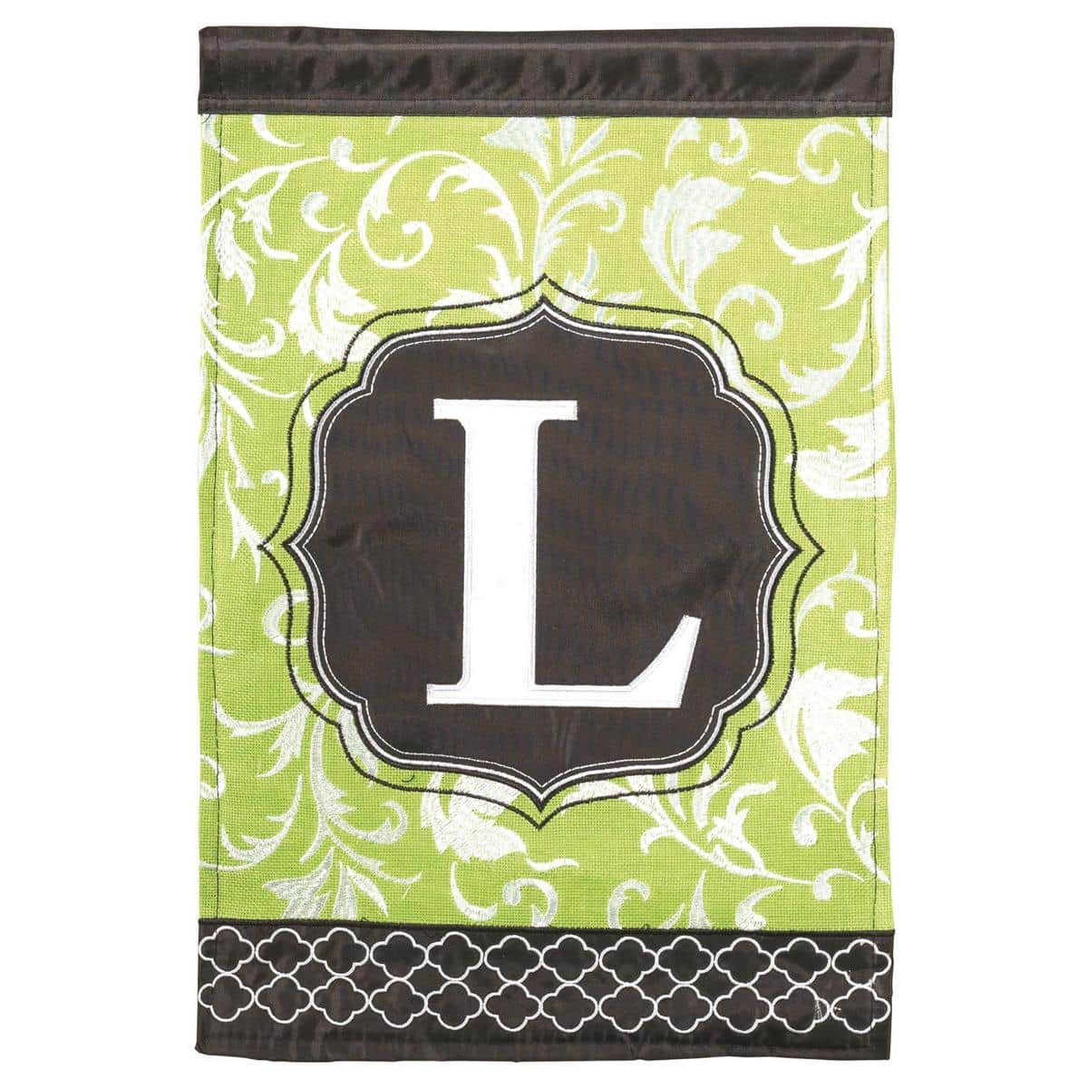 Green and black double applique 13x18 garden flag with bold letter L, displayed on a standard stand by an entryway for personalized outdoor decor