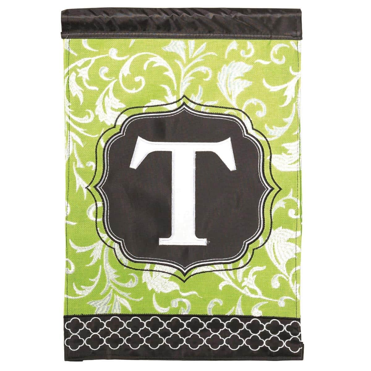 13x18 Monogram T garden flag in green and black with double applique monogram displayed on a standard metal garden flag stand in a landscaped front yard setting.