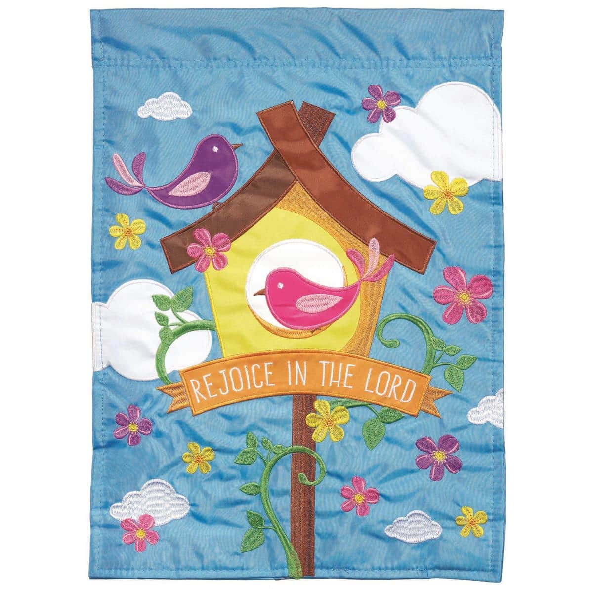 Rejoice In The Lord garden flag 13x18 double applique featuring raised script, layered applique cross and decorative floral motifs on a neutral background shown hanging on a garden flag pole near a porch.