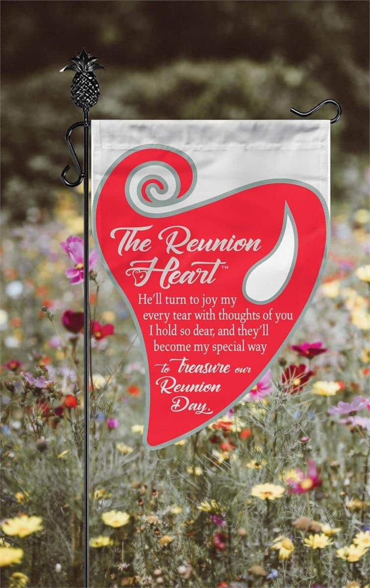 Reunion Heart Burlap Garden Flag 13x18 double applique bereavement garden flag with rustic burlap texture and layered heart motif displayed on a small garden pole near flowers and memorial stones.