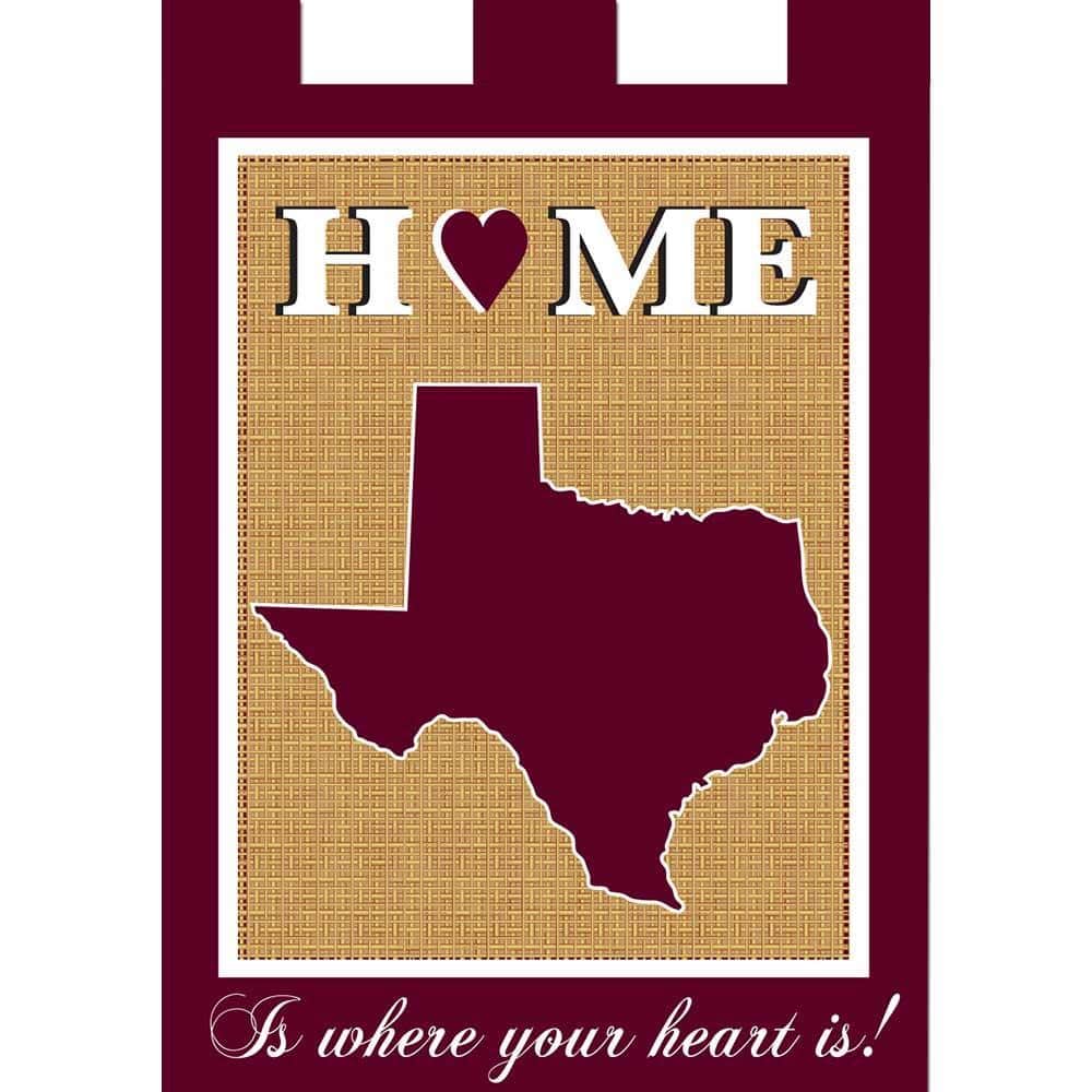 13x18 maroon and white Texas Home garden flag with double applique design displayed on a yard stake beside a welcome mat and potted plants, showing bold lettering and layered fabric detail.
