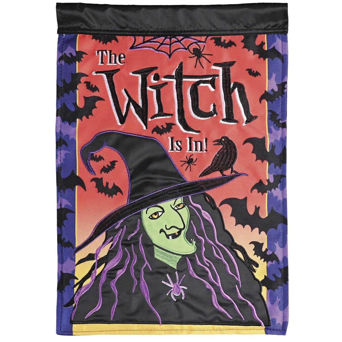 Front view of The Witch Is In 29x42 HallowWitch double-applique-plus banner flag with embroidered witch silhouette, broom, moon, spooky lettering, and layered applique textures staged on a porch pole for Halloween display.