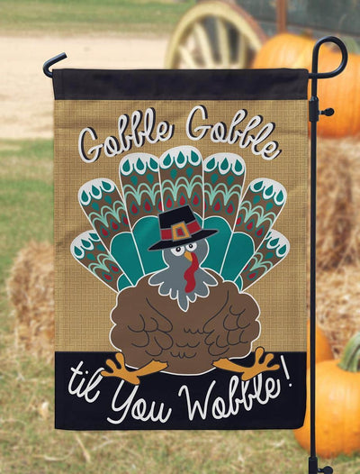 13x18 inch Turkey burlap garden flag with layered double applique turkey motif on rustic burlap background displayed on a metal garden flag stand in a fall porch scene