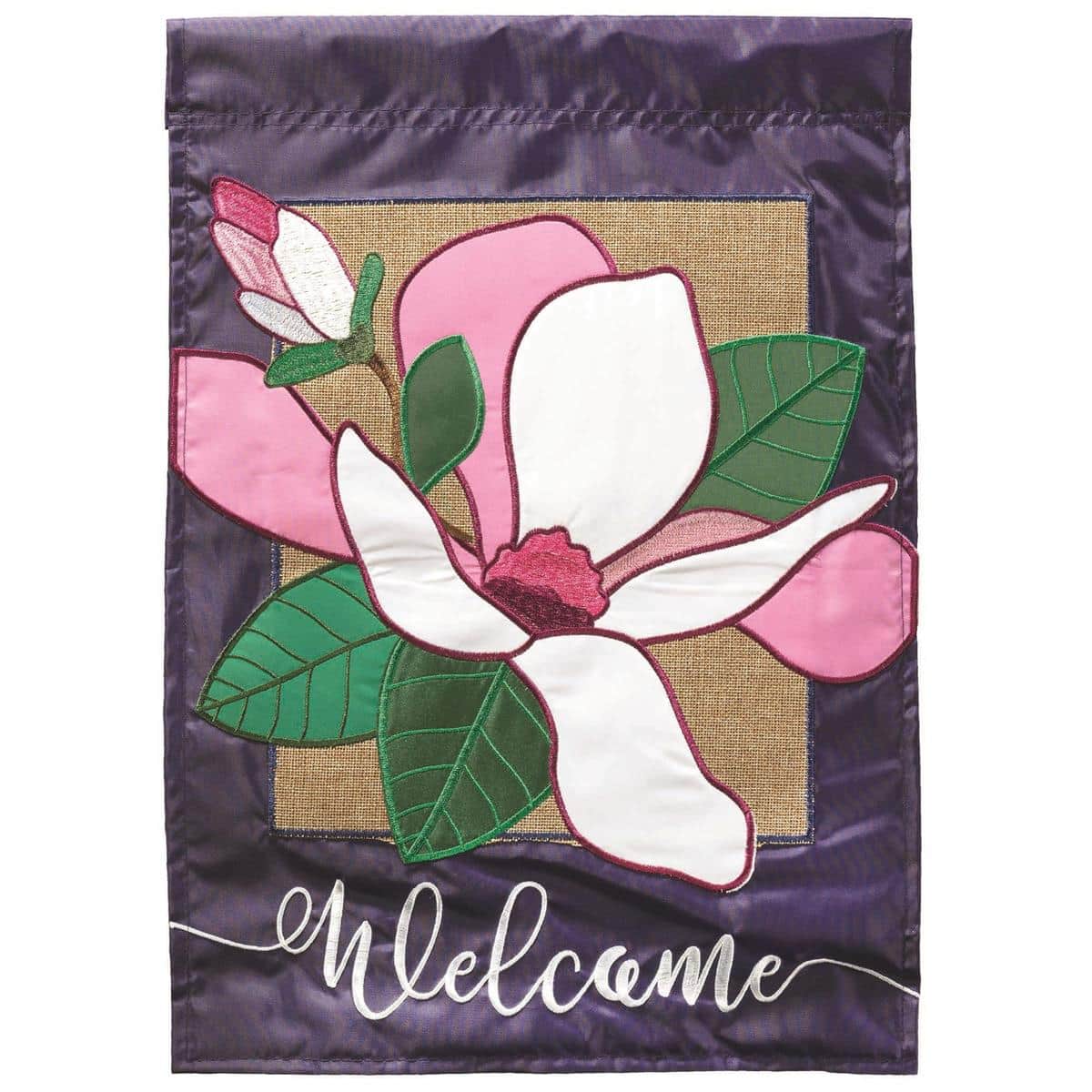 13x18 welcome magnolia burlap garden flag with layered double applique magnolia blossoms on burlap-textured background, shown hanging on a standard garden flag pole in a front porch setting.