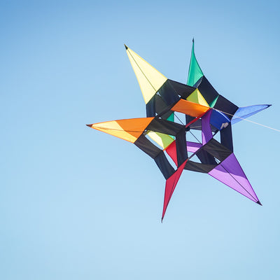 AeroStar Supersize Ultra 3D Kite soaring high with a vibrant star design against a clear blue sky on a sunny day.