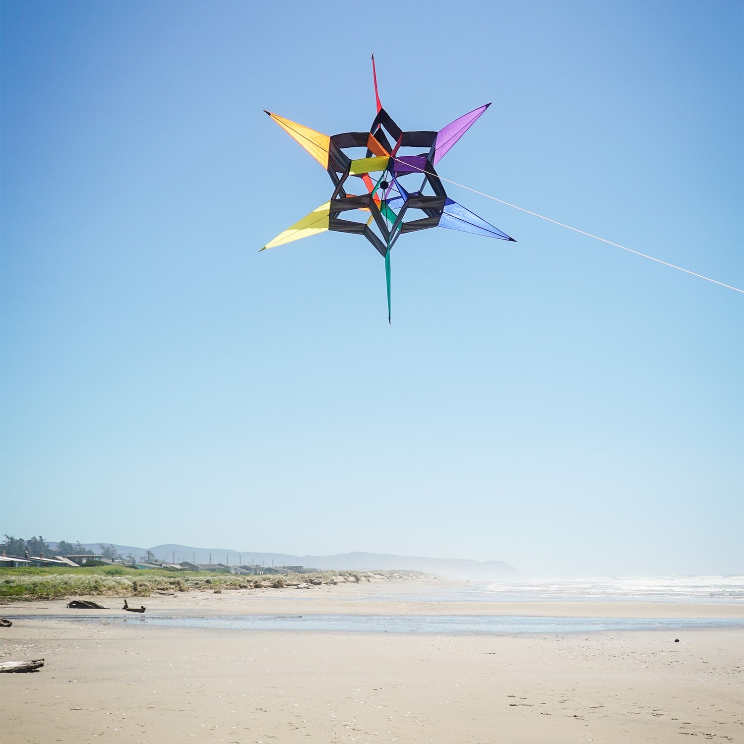 AeroStar Supersize Ultra 3D Kite soaring high with a vibrant star design against a clear blue sky on a sunny day.