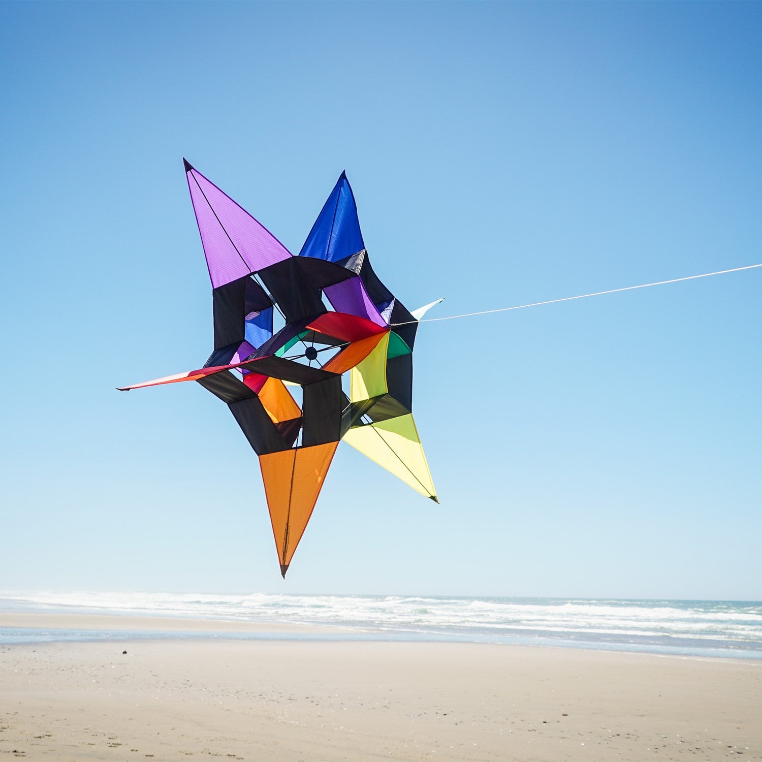 AeroStar Supersize Ultra 3D Kite soaring high with a vibrant star design against a clear blue sky on a sunny day.