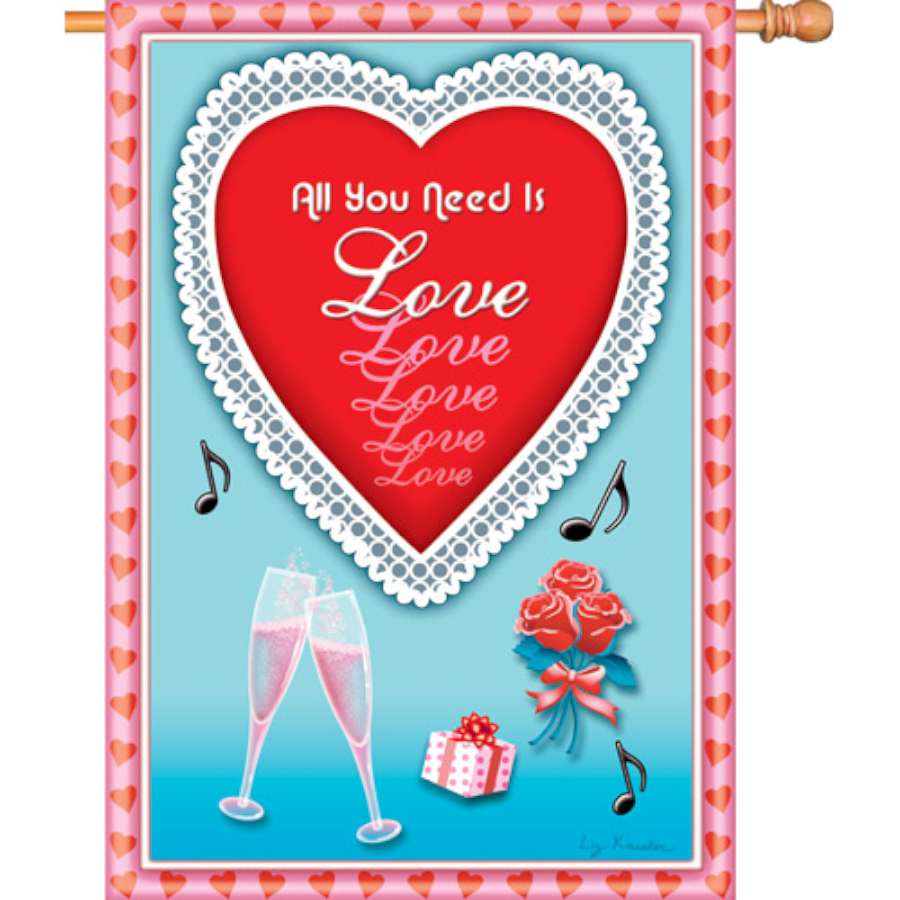 28 in. All You Need Is Love flag featuring bright colors and a cheerful design, displayed in a garden setting to enhance outdoor decor.