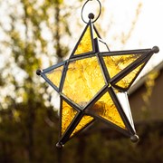 Amber 5-Point Star Hanging Tealight Lantern featuring textured glass and metal accents hanging in a bright indoor space.
