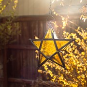 Amber 5-Point Star Hanging Tealight Lantern featuring textured glass and metal accents hanging in a bright indoor space.