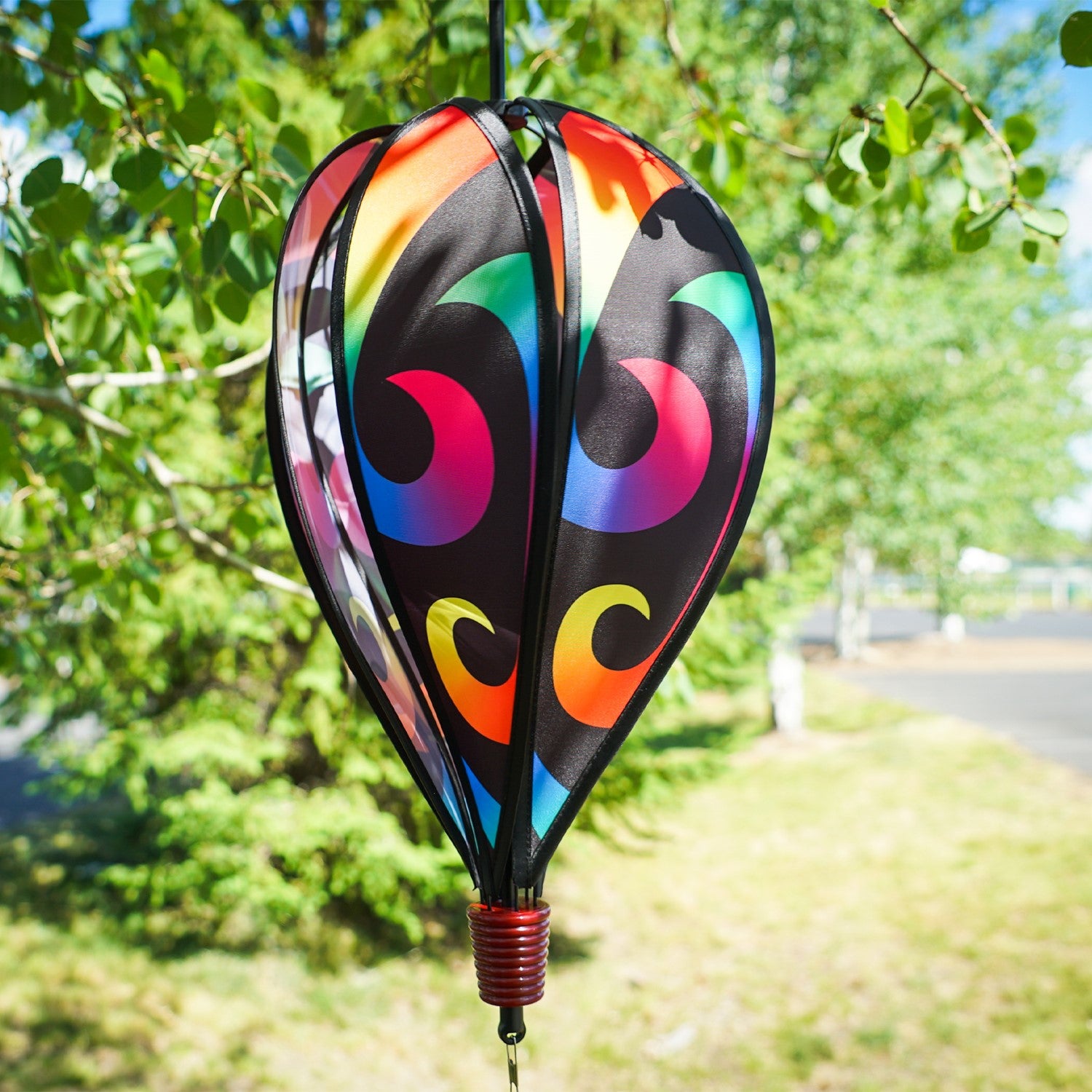 Aurora 6-Panel Hot Air Balloon in vibrant rainbow colors, displayed in a garden setting, spinning gracefully with colorful tail.