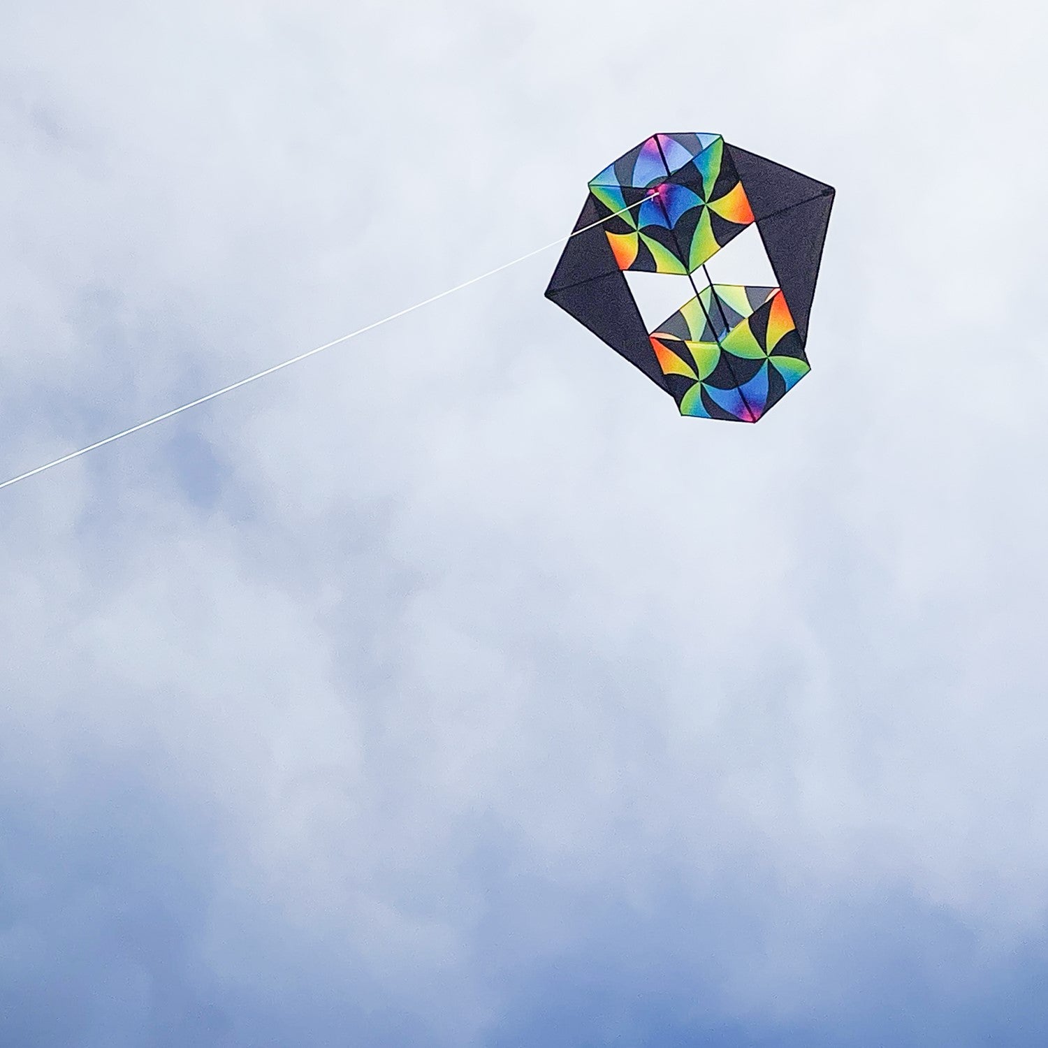 Aurora Winged Double Box Kite soaring high with its vibrant wings against a clear blue sky, showcasing its colorful design during flight.