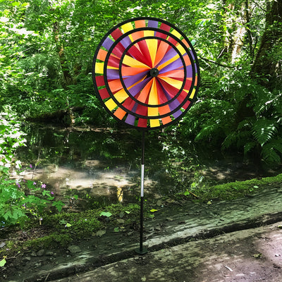 Vibrant Autumn Triple Wheel Spinner featuring three colorful wheels dancing in the wind, showcasing fall hues of red, orange, and yellow in a garden setting.