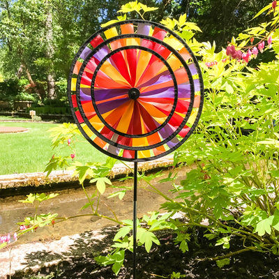 Vibrant Autumn Triple Wheel Spinner featuring three colorful wheels dancing in the wind, showcasing fall hues of red, orange, and yellow in a garden setting.