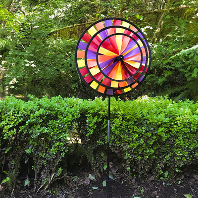 Vibrant Autumn Triple Wheel Spinner featuring three colorful wheels dancing in the wind, showcasing fall hues of red, orange, and yellow in a garden setting.