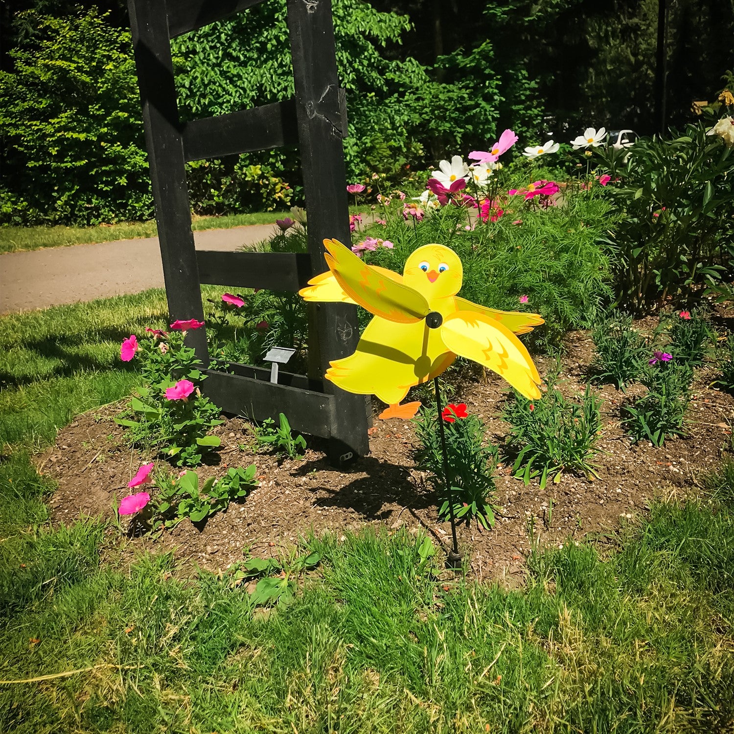 Baby Chick Whirligig featuring a cute yellow chick design spinning in the breeze in a garden setting, crafted from durable materials.