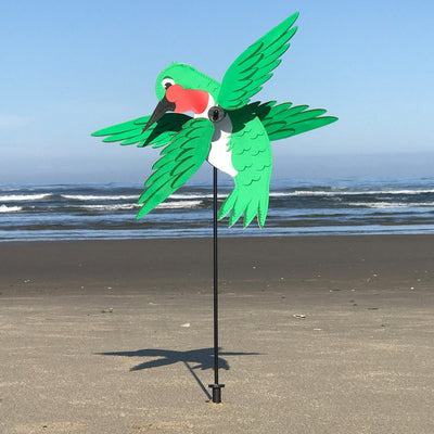 Baby Hummingbird Whirligig in bright colors spins in a garden setting, showcasing its whimsical design and durable construction.