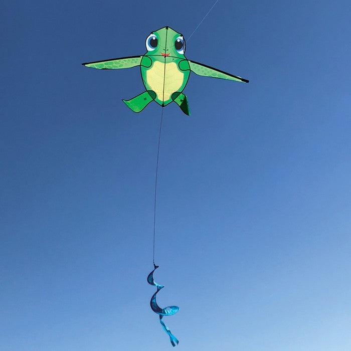 Baby Tortuga Kite featuring a cute sea turtle design and spinning tail, displayed in a clear blue sky during a sunny outdoor event.