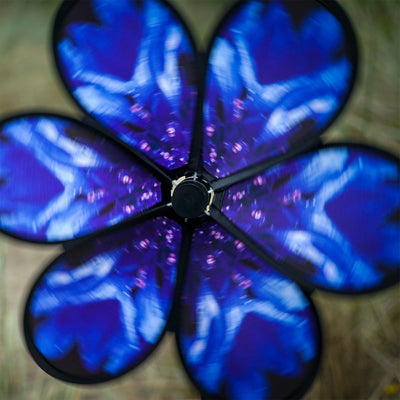 Vibrant 13.5-inch Bachelor Button Spinner with realistic blue flower and green leaves spinning on a fiberglass pole in a garden setting.