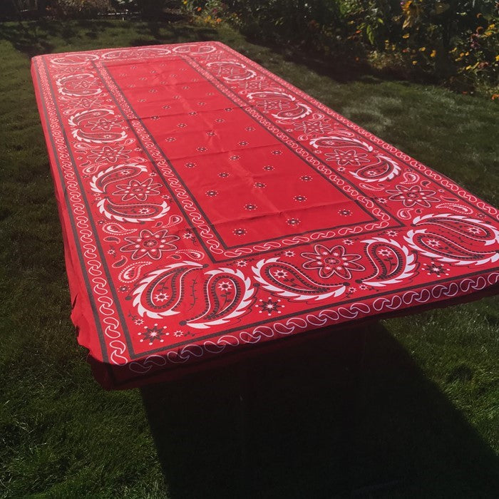 Bandana 8' Tablecloth with vibrant design displayed on a picnic table in a sunny outdoor setting, secured with deep pockets.