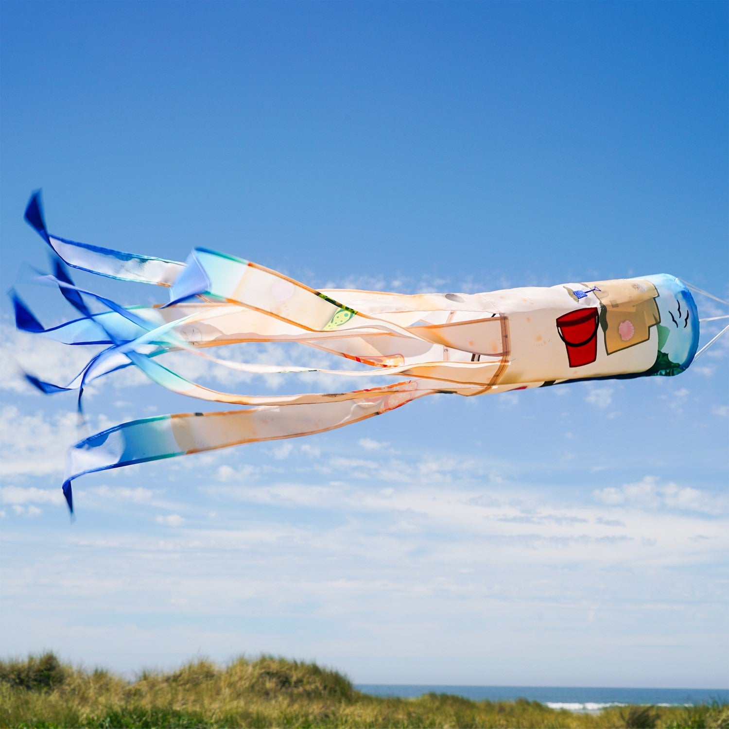Beach Day 40-inch Illusion Windsock with vibrant beach-themed design and embroidered details, fluttering in a garden setting.