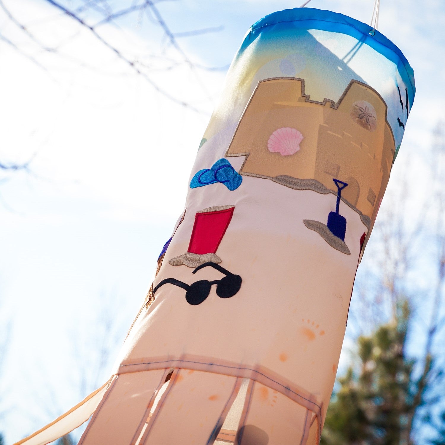 Beach Day 40-inch Illusion Windsock with vibrant beach-themed design and embroidered details, fluttering in a garden setting.