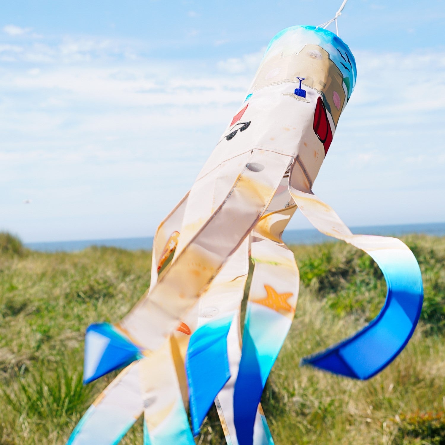 Beach Day 40-inch Illusion Windsock with vibrant beach-themed design and embroidered details, fluttering in a garden setting.