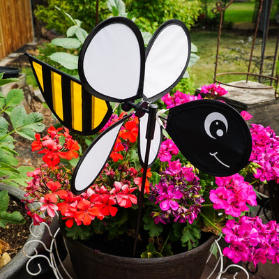 Bee Baby Spinner with colorful 12-inch wheel and bee design, elegantly spinning in a sunny garden setting on a fiberglass pole.