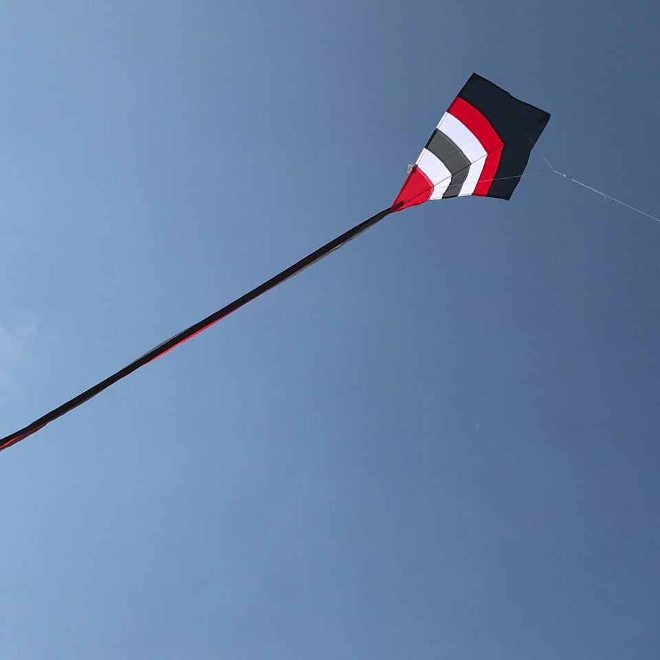 Blazer Arch 27" Diamond Kite with colorful arcs displayed against a blue sky, showcasing its vibrant design and tails.
