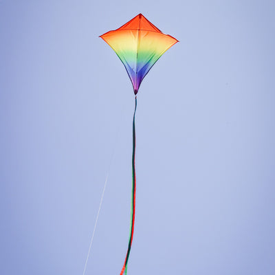 Blended Rainbow 30-inch diamond kite showcasing vibrant colors with flowing tails, soaring against a blue sky during a sunny day.