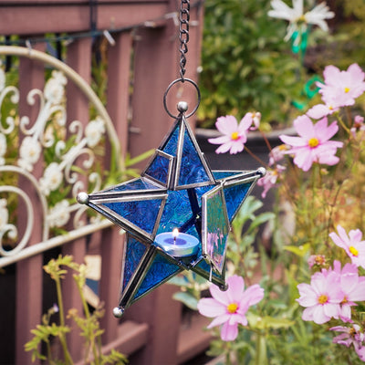 Blue 5-Point Star Hanging Tealight Lantern with textured glass panels and metal frame, suspended elegantly with a chain in an outdoor setting.