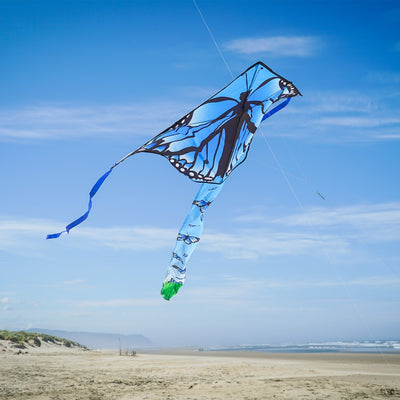 Blue Butterfly Swarm 45 inch Fly-Hi Kite soaring in the sky, showcasing a vibrant blue karner butterfly design with streamer tails.
