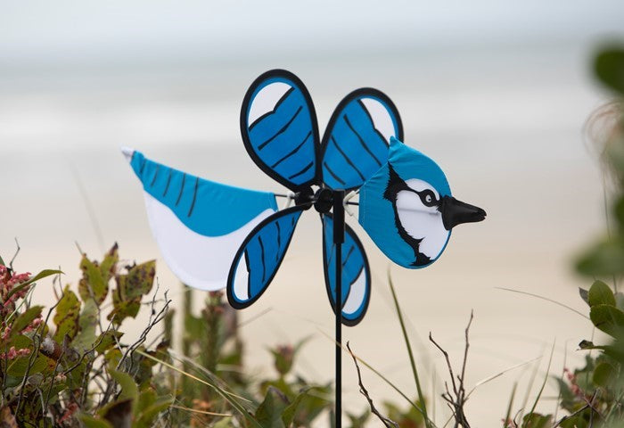 Blue Jay Baby Spinner vividly displayed in a garden setting, featuring colorful design and 12-inch spinning wheel for outdoor charm.