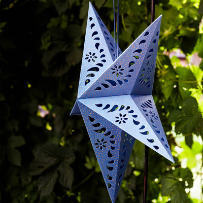 Blue Paper Star Lantern with intricate cutouts, hung indoors, providing a glowing ambiance in a boho-inspired setting.