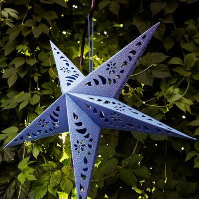 Blue Paper Star Lantern with intricate cutouts, hung indoors, providing a glowing ambiance in a boho-inspired setting.