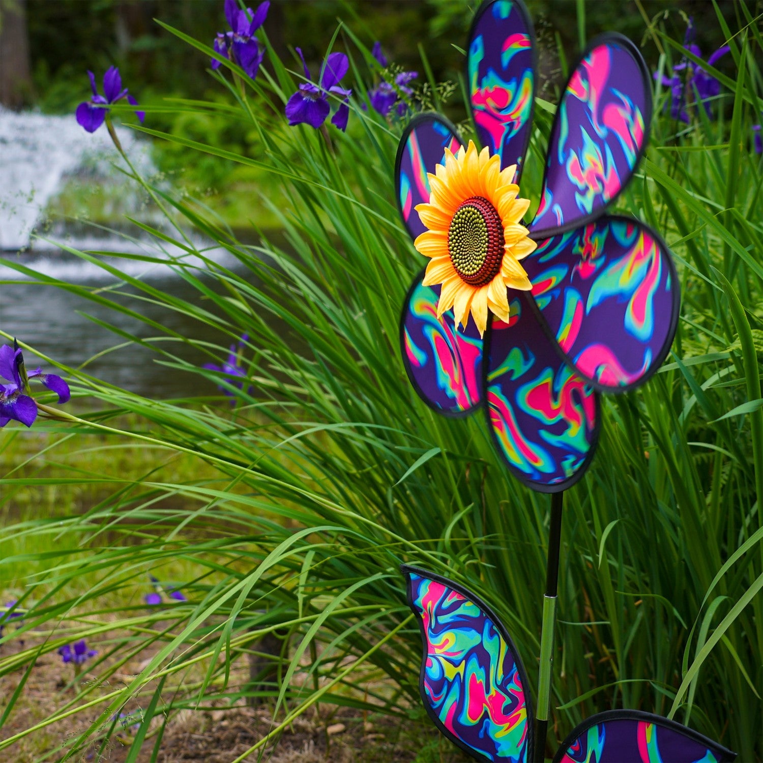 16 inch Blue Psychedelic Flower with Leaves garden spinner showcasing six petals, sunflower center, and leaves attached to a stand in a vibrant outdoor setting.