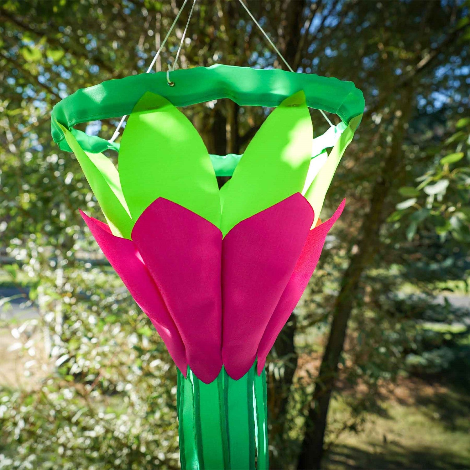 Bright Green 38 inch Lotus Flower Windsock with colorful petals and flowing green tails displayed in a garden setting under clear skies.