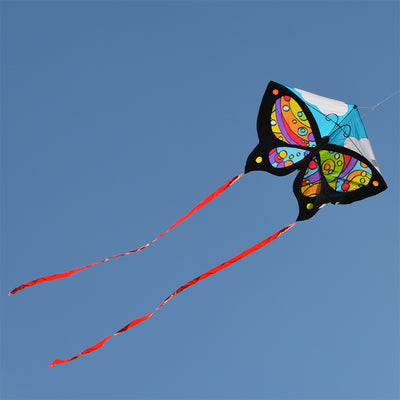 Butterfly Kite - Rainbow Orbit soaring in a clear sky, showcasing its vibrant butterfly design and ripstop polyester fabric against the sun.