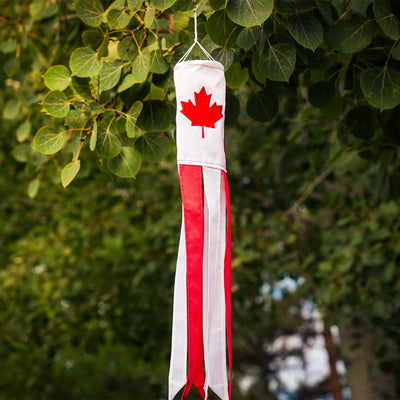 Canada 18-inch windsock displaying a bright maple leaf design, fluttering in the breeze outdoors with six colorful tails.