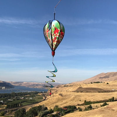 Vibrant Cardinal Hot Air Balloon spinner with cardinal and plumeria design, spinning gracefully in a garden setting to showcase its colorful features.