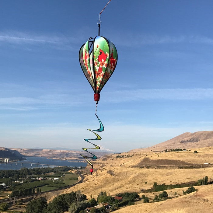 Vibrant Cardinal Hot Air Balloon spinner with cardinal and plumeria design, spinning gracefully in a garden setting to showcase its colorful features.