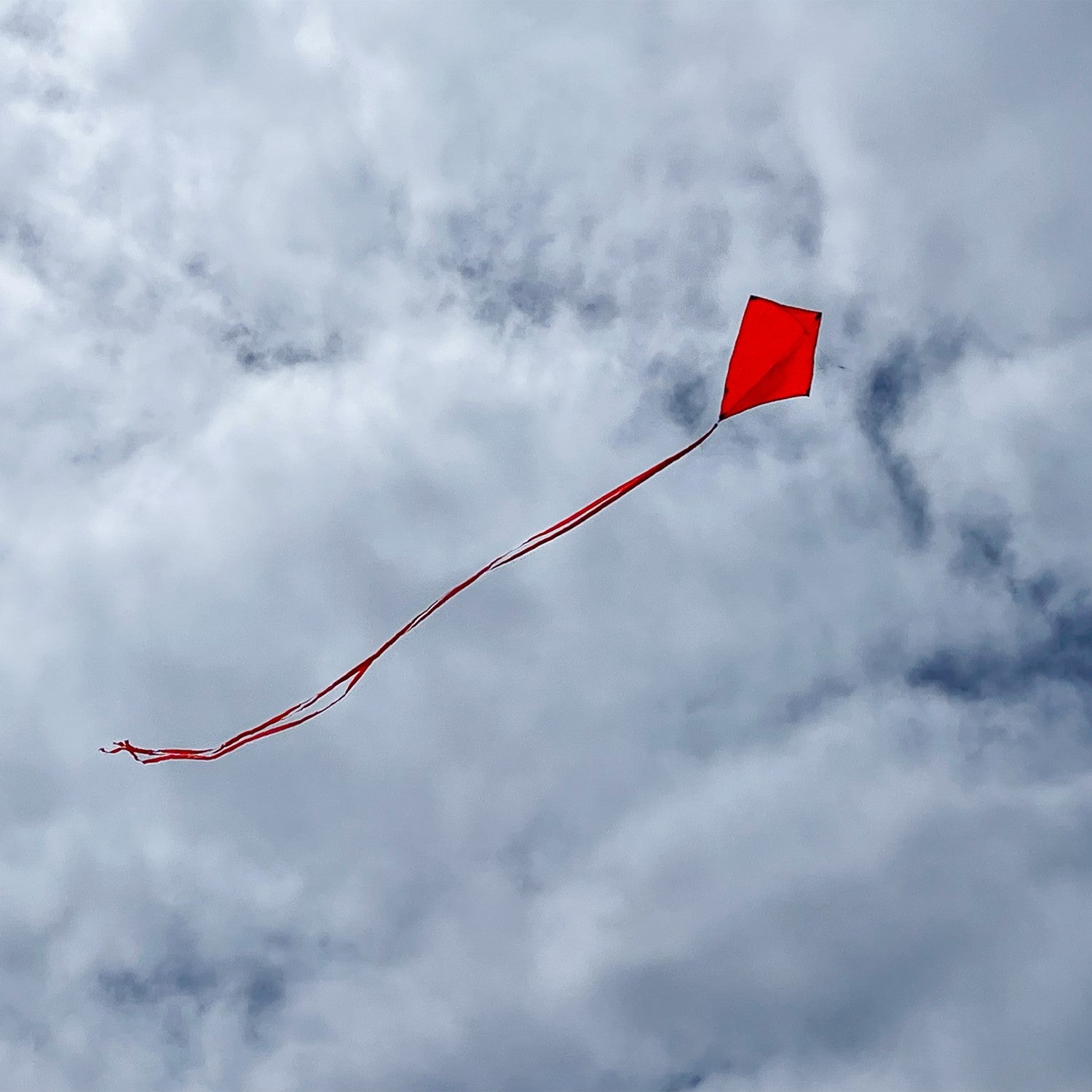 Cherry Colorfly 30-inch diamond kite with three color-coordinated tails flying in a blue sky, showcasing its vibrant solid color design.
